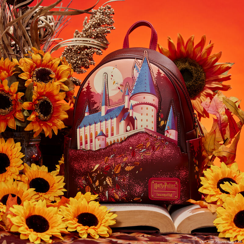 Image of our Hogwarts Fall Leaves Mini Backpack sitting on a book and surrounded by flowers